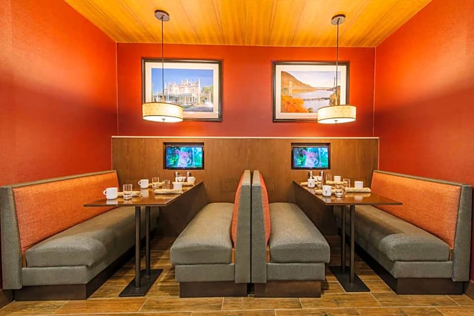 Orange dining room with booth seating and TV screens