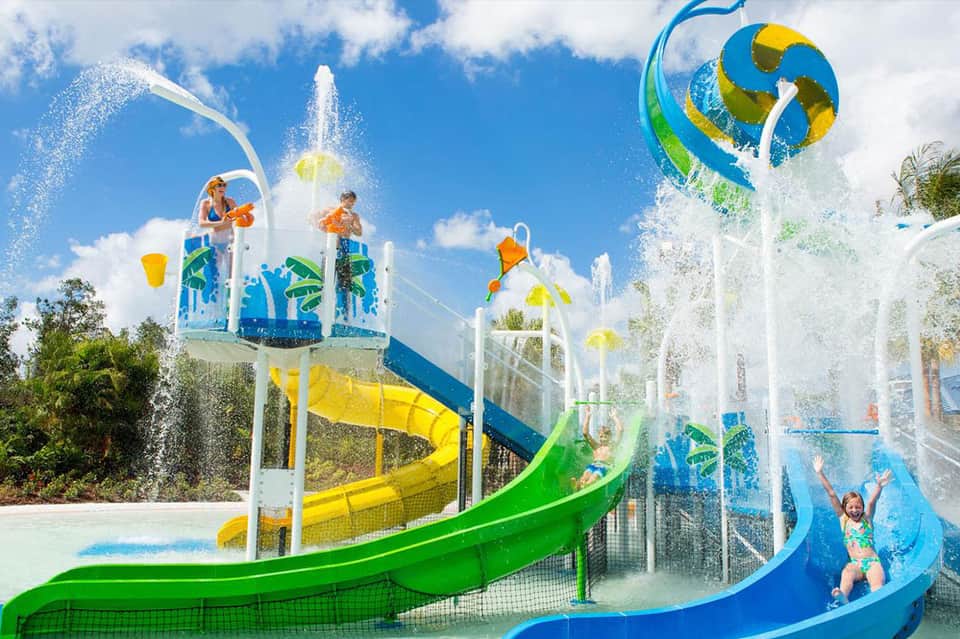 Colorful water park splash pad with blue and green slides and water features