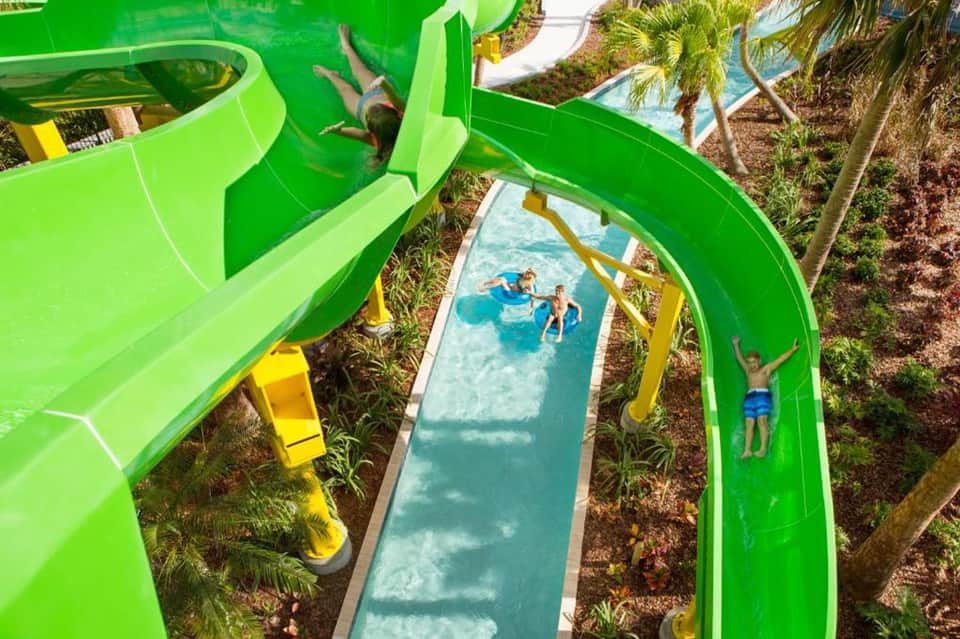 Green water slides at tropical resort with families enjoying the attraction