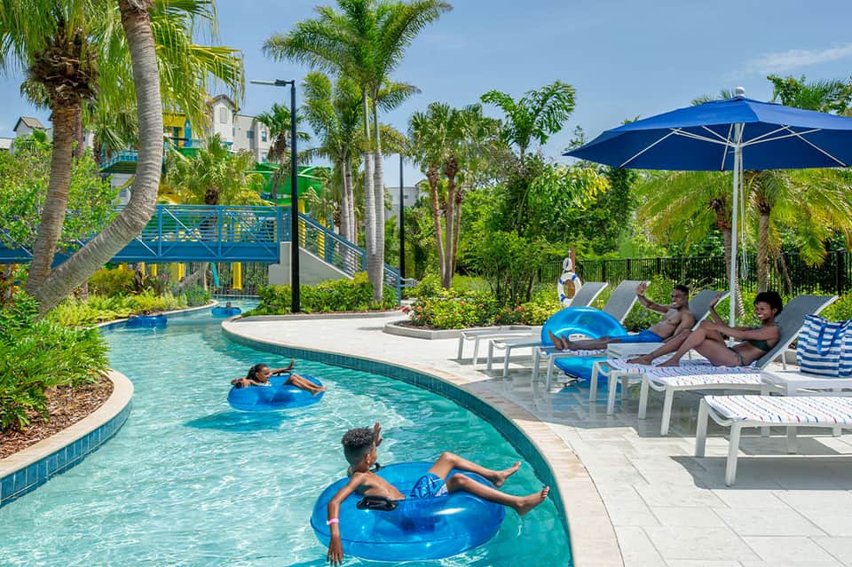 Resort lazy river and pool area with families enjoying water activities and tropical landscaping