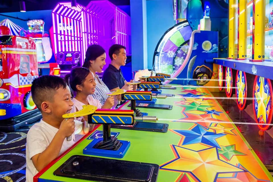 Children and adults playing arcade games with neon lights and colorful game displays