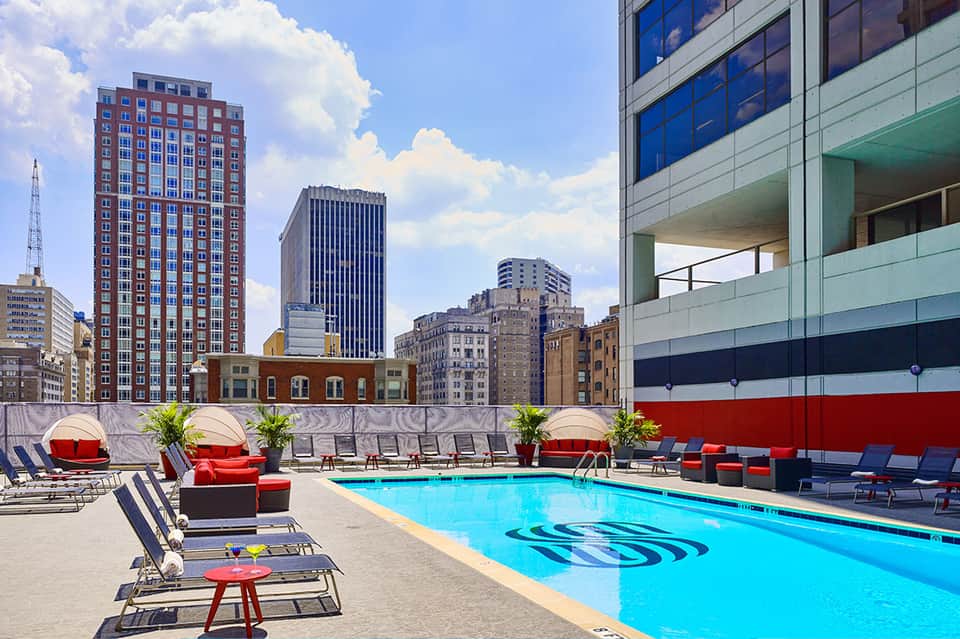 Urban rooftop pool with bright blue water and city skyline backdrop