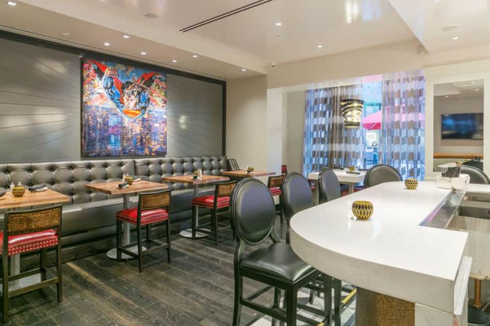 Contemporary restaurant with gray tufted banquette, modern artwork, and city views