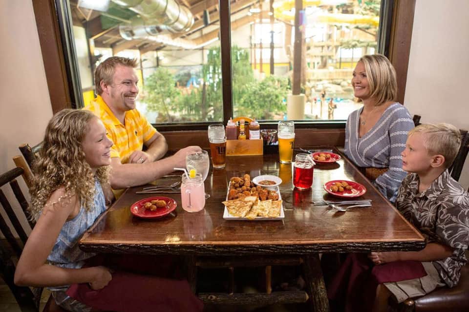 Family dining at resort restaurant with water park view visible through windows