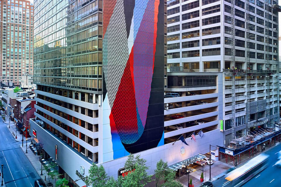 Urban hotel building with colorful red and blue curved abstract street art mural on facade