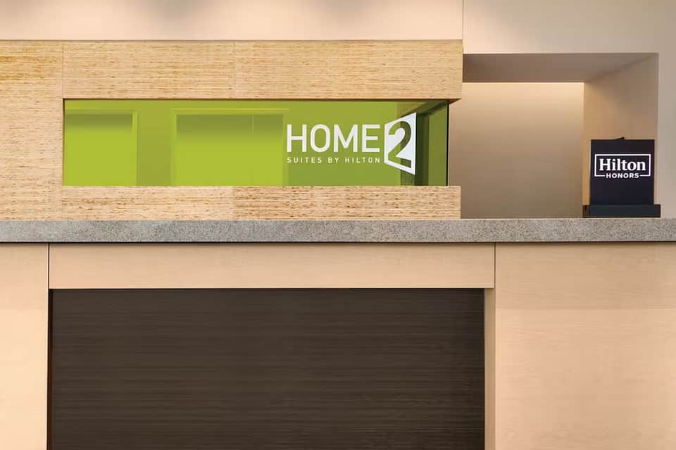 Home2 Suites by Hilton hotel check-in desk with lime green accent wall and modern design