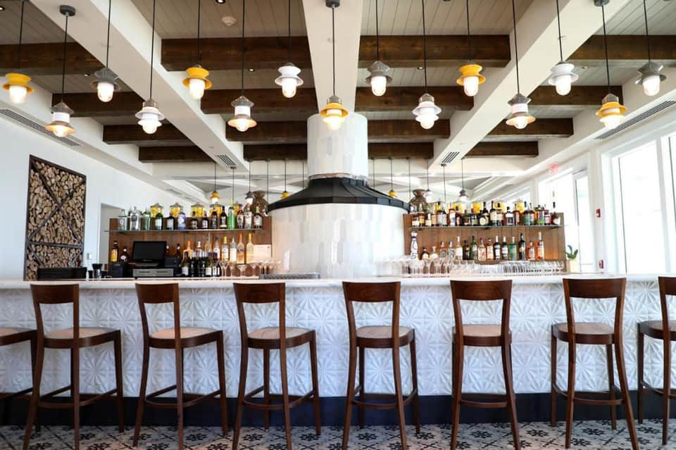 Upscale resort bar with wooden ceiling beams, pendant lights, extensive liquor selection, and wood chairs
