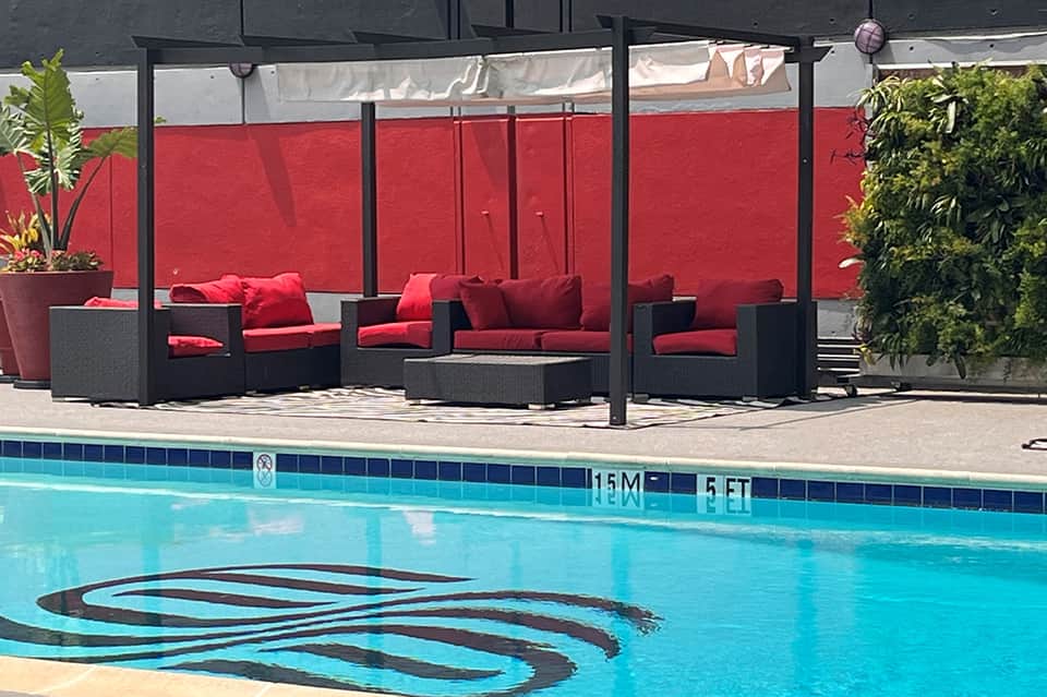 Resort pool with red cushioned lounge seating area and shade structure