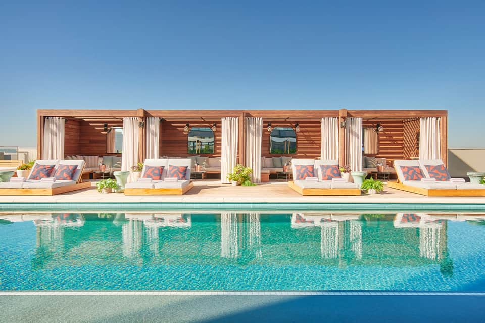 Luxury cabanas with wooden structures beside a bright turquoise swimming pool
