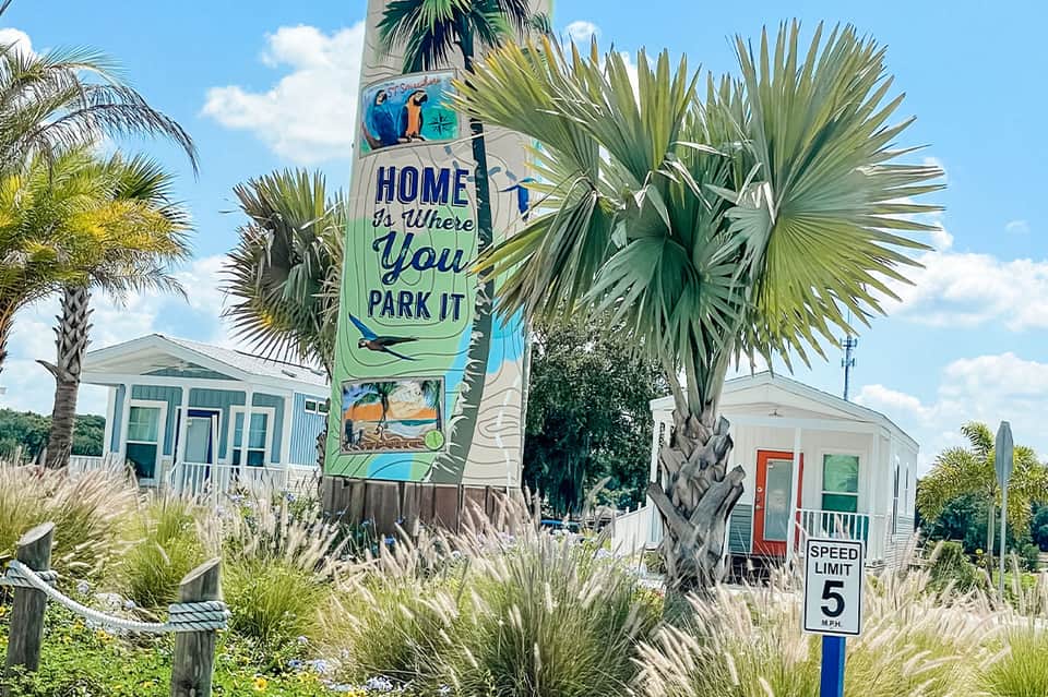 Colorful beach community sign with painted palm tree and mobile home neighborhood