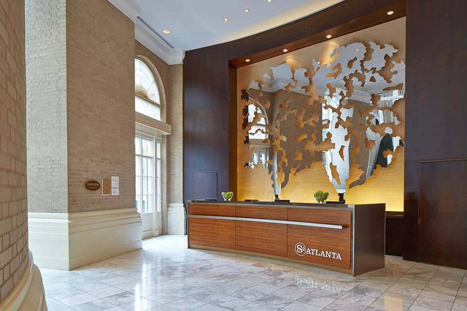 Elegant hotel lobby with wooden world map art, brick walls, and polished marble floors