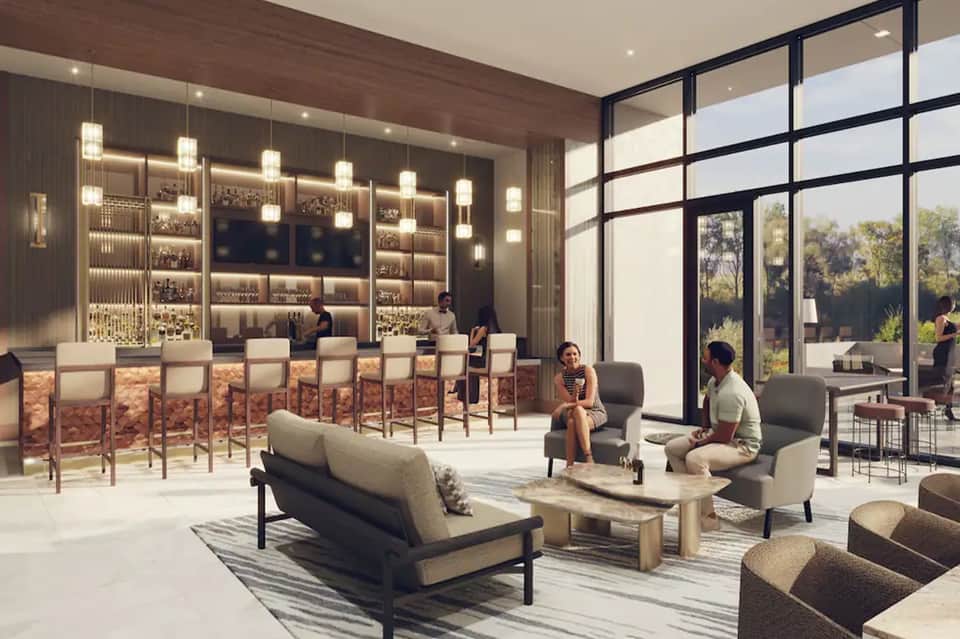 Modern hotel bar and lounge with illuminated shelving, seating, and glass views