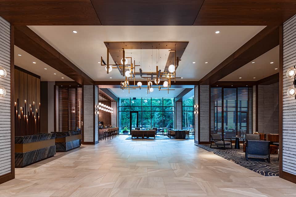 Contemporary hotel lobby with wood accents, modern chandelier, and floor-to-ceiling windows