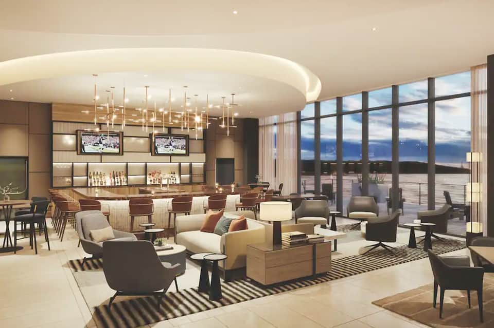 Upscale resort bar and lounge with modern pendant lights, ocean view windows, and seating