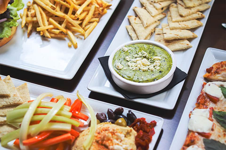 Appetizer spread with hummus, crackers, fries, vegetables, and various Mediterranean dishes