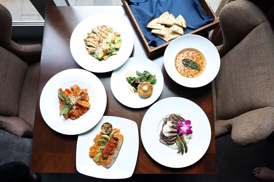 Gourmet plated dishes overhead including seafood, pasta, and appetizers with white plates