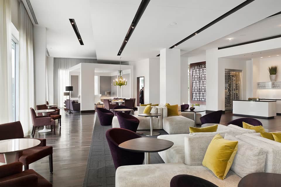 Contemporary hotel lobby lounge with cream and burgundy seating, yellow accent pillows
