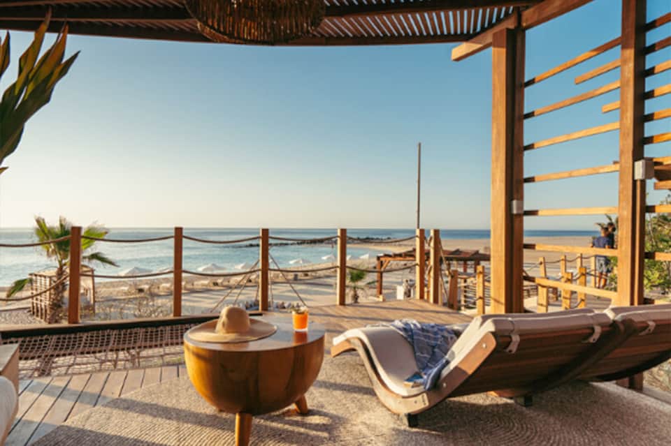 Beachfront deck with wooden pergola, lounger, ocean view, and natural wood railings