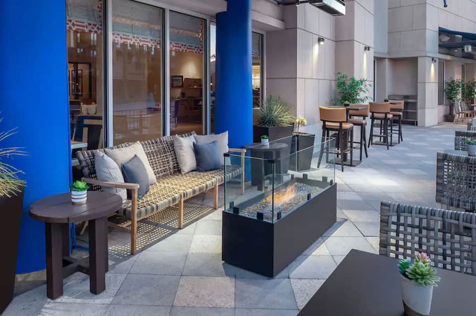 Contemporary hotel courtyard with blue column, seating area, and fire feature