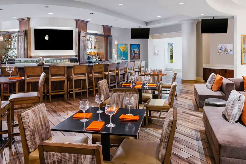 Resort lounge and bar area with wooden furnishings, flat-screen TVs, bar counter, and modern décor
