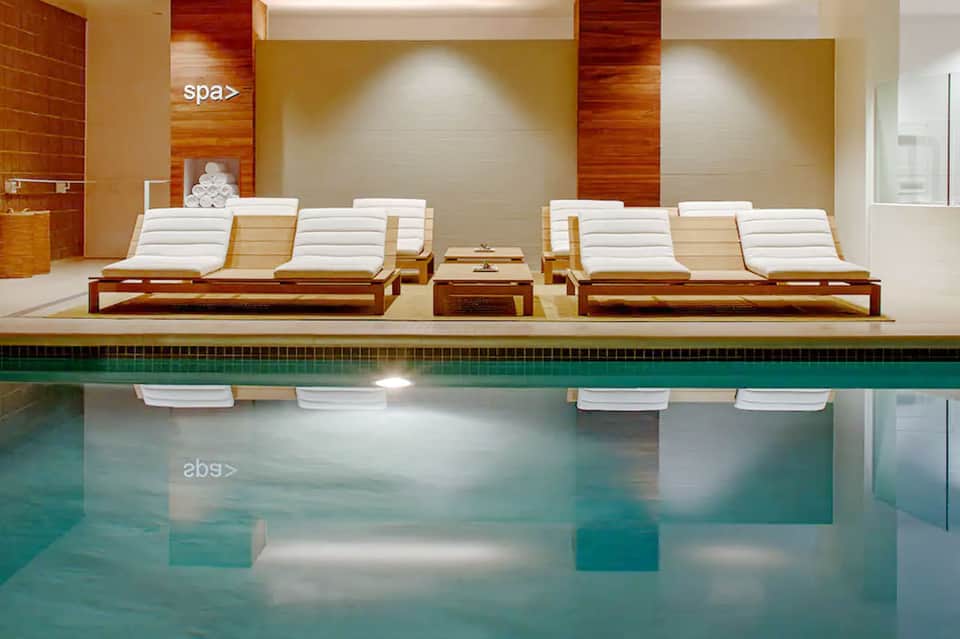 Indoor spa area with wooden lounge chairs, towels, and indoor pool