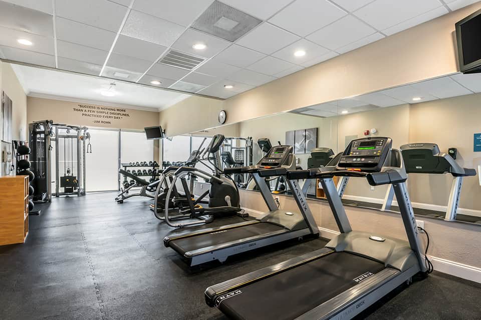 Modern gym with treadmills, exercise equipment, and motivational quote on wall