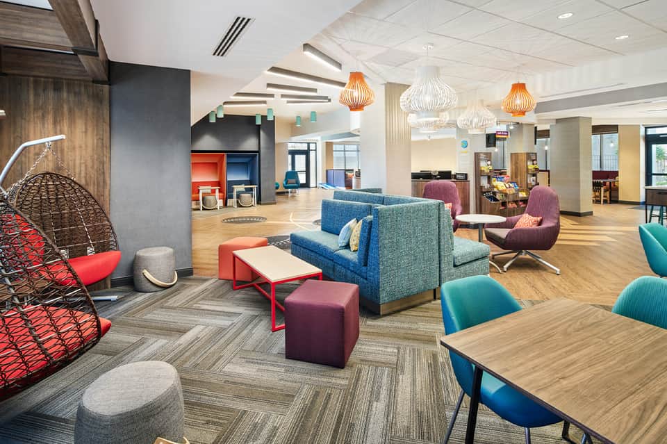 Contemporary hotel lobby with colorful seating, pendant lights, and open layout