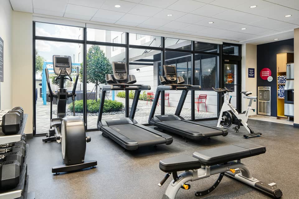 Fitness center with treadmills and stationary bikes near large windows