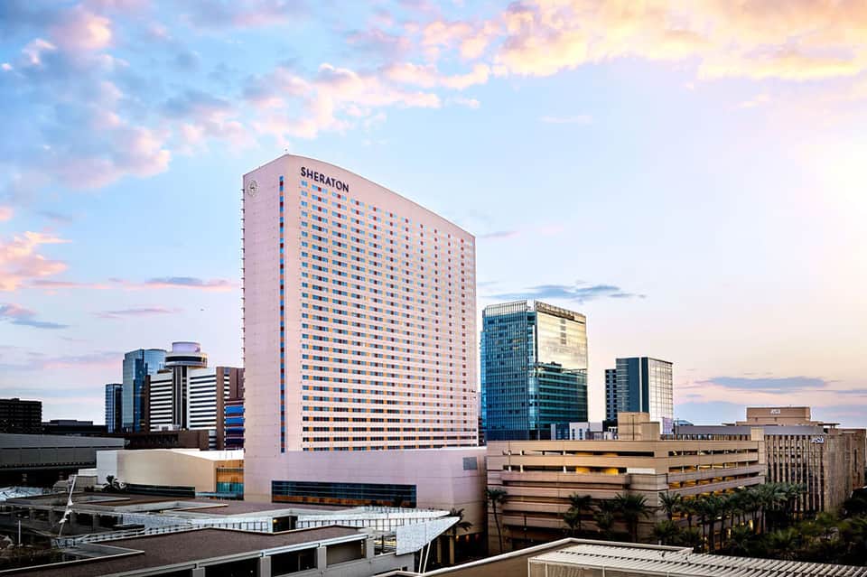 Sheraton high-rise hotel tower at dusk with pink sky and downtown cityscape