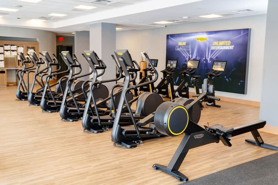 State-of-the-art fitness facility with rows of elliptical machines and large entertainment screen