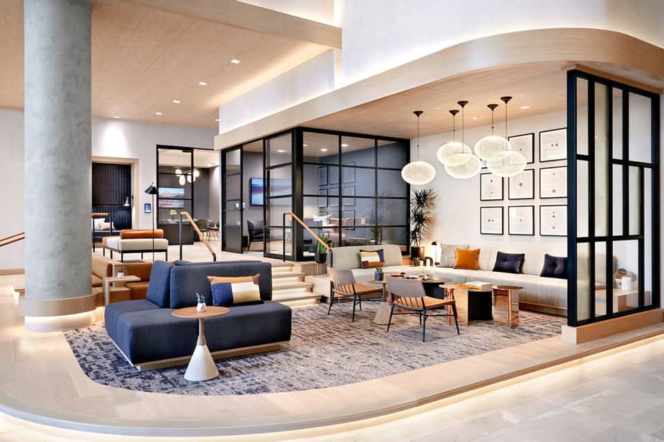 Contemporary hotel lobby with curved blue sofa, pendant lights, and modern interior design