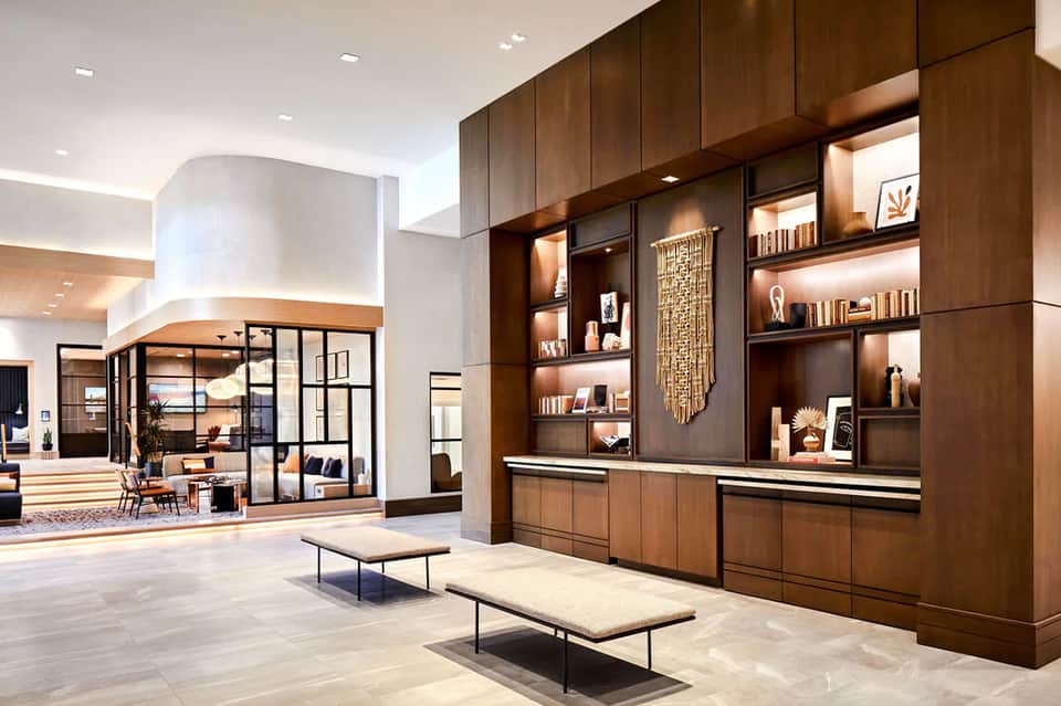 Modern hotel lobby with dark wood shelving and marble reception desk