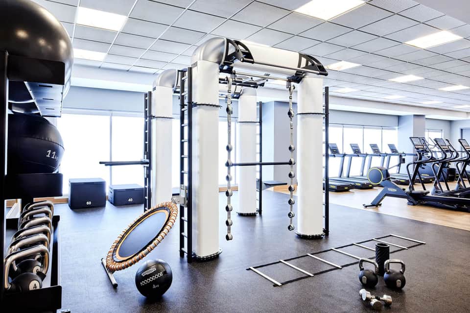Modern gym with equipment including pull-up bar, dumbbells, and treadmills