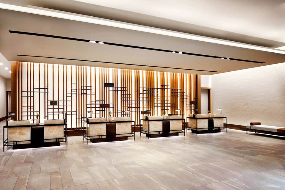 Elegant lobby reception area with geometric wood screen divider and marble flooring