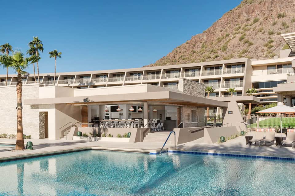 Modern resort pool with mountain backdrop and multi-story hotel building