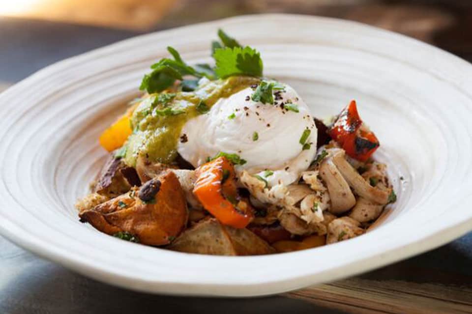 Gourmet dish with seared meat, poached egg, and vegetables on white plate