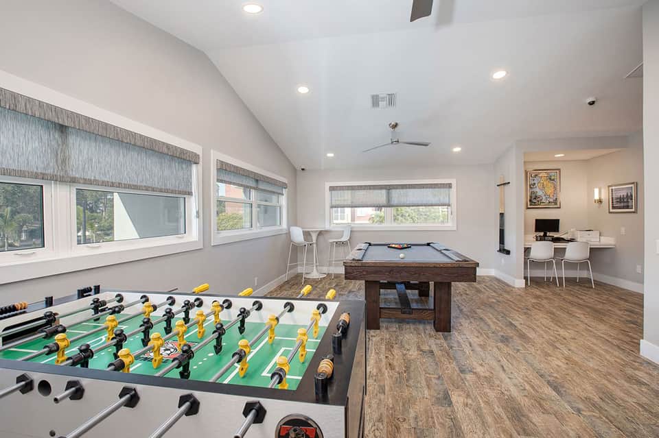 Game room with foosball table and billiards table, modern interior with windows