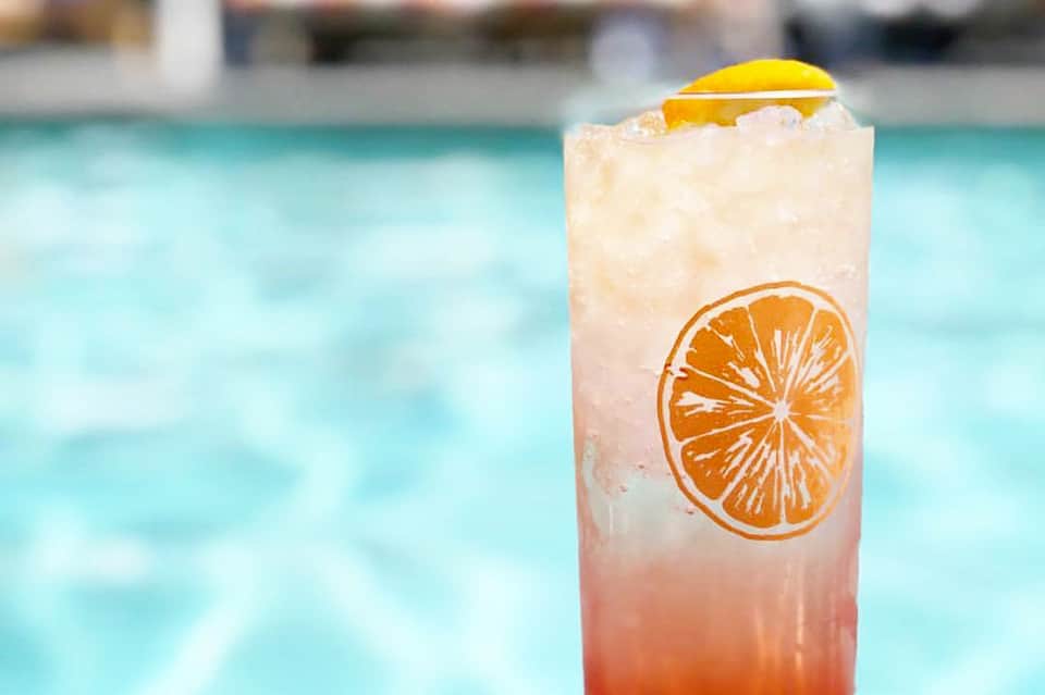 Tropical cocktail with orange slice and lemon wheel over ice by resort pool