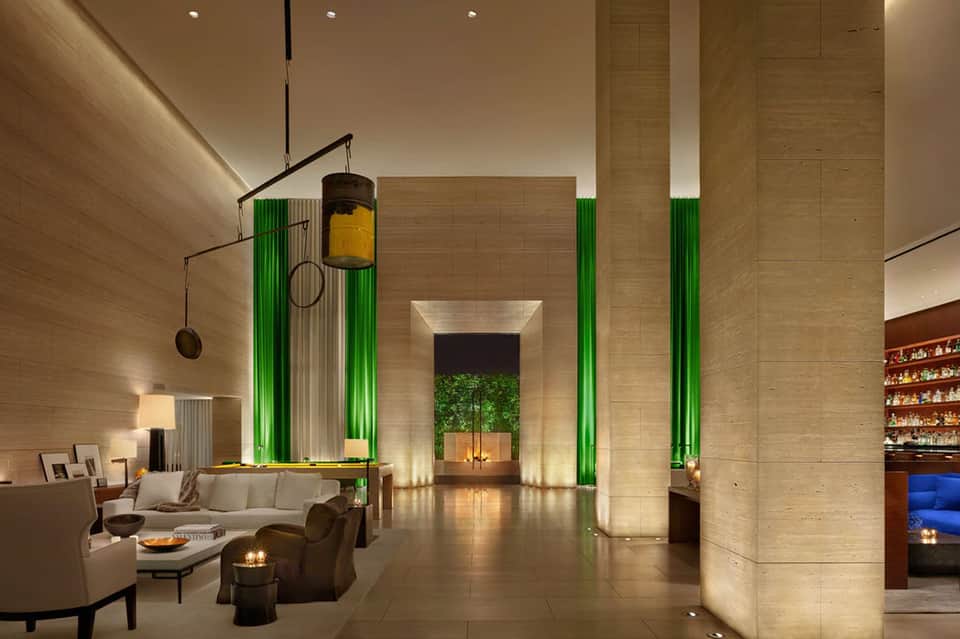 Modern hotel lobby with soaring ceilings, dramatic green lighting, and contemporary furnishings