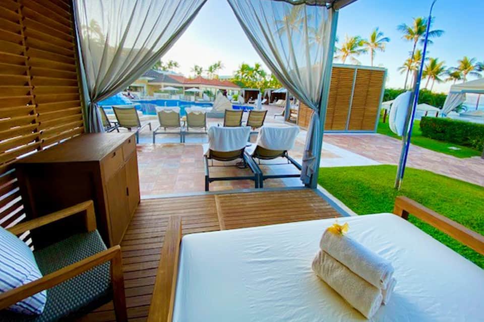 Luxury cabana bedroom overlooking pool courtyard with sheer curtains and manicured lawn