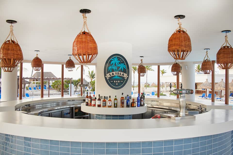 Beach bar with woven pendant lights, tropical views, and full liquor selection backdrop