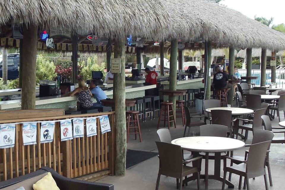 Beachfront tiki bar with thatch roof and casual seating area