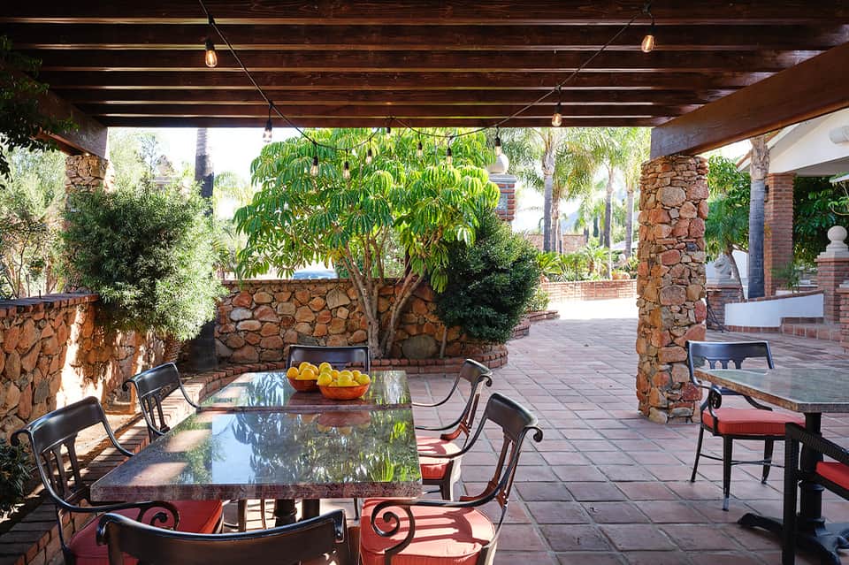 Rustic terrace with stone columns, wooden pergola and dining tables