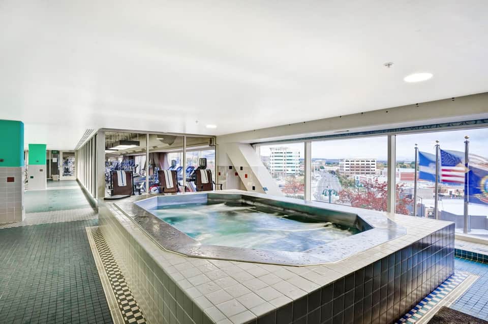 Indoor hot spring pool with colorful water and city views through large windows