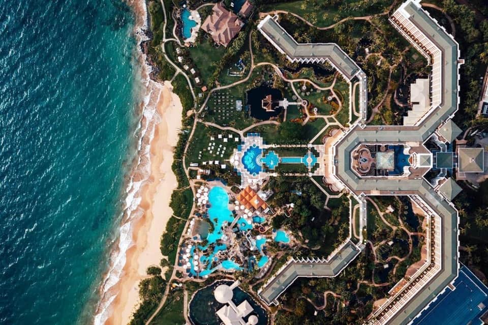 Aerial view of luxury beachfront resort with multiple pools, manicured grounds, and pristine turquoise ocean