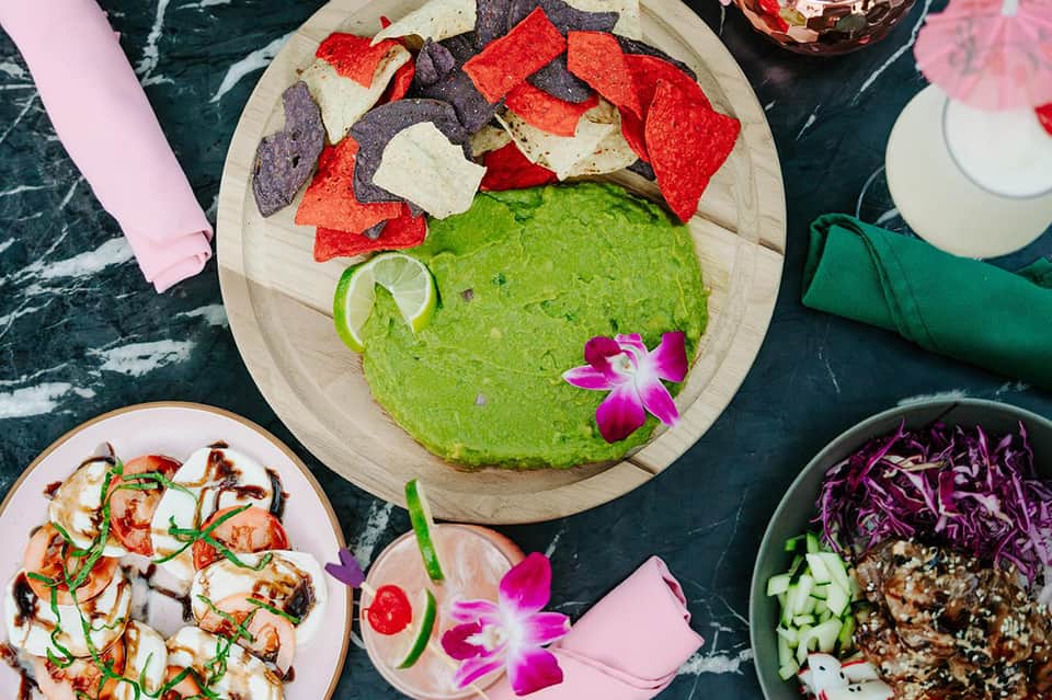 Colorful Mexican appetizers with guacamole, tortilla chips, and fresh lime garnish