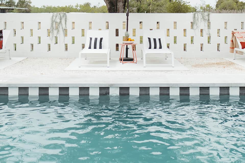 Poolside loungers with white wall backdrop and tropical vegetation