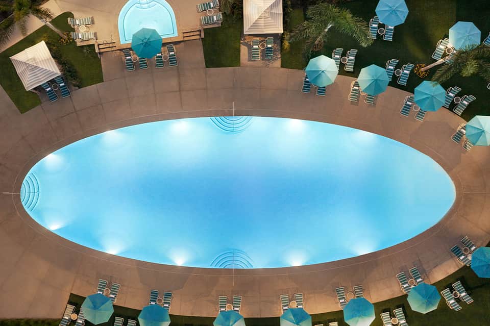Aerial view of large oval-shaped pool surrounded by lounge chairs and umbrellas
