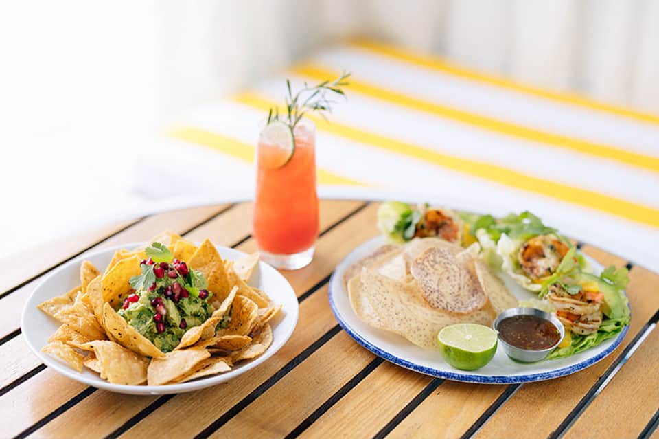 Beachside dining with nachos, fish tacos, and coral-colored cocktail