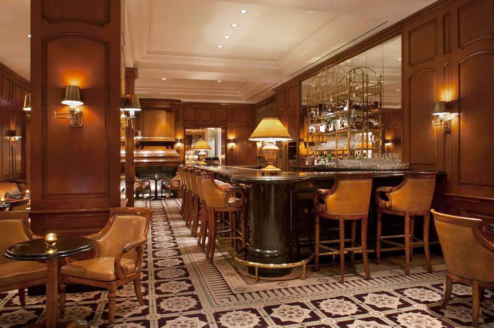 Upscale bar lounge with mahogany wood paneling, leather seating, and professional bar setup